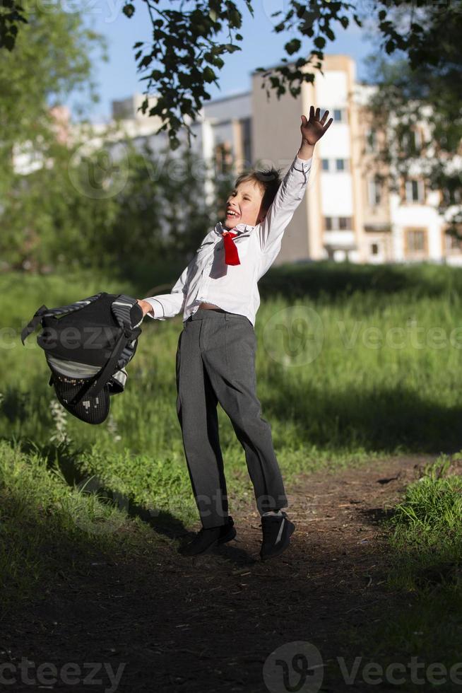 une content écolier jette en haut le sien école sac à dos et se réjouit à le début de le vacances. le fin de le école année et le début de le vacances. photo