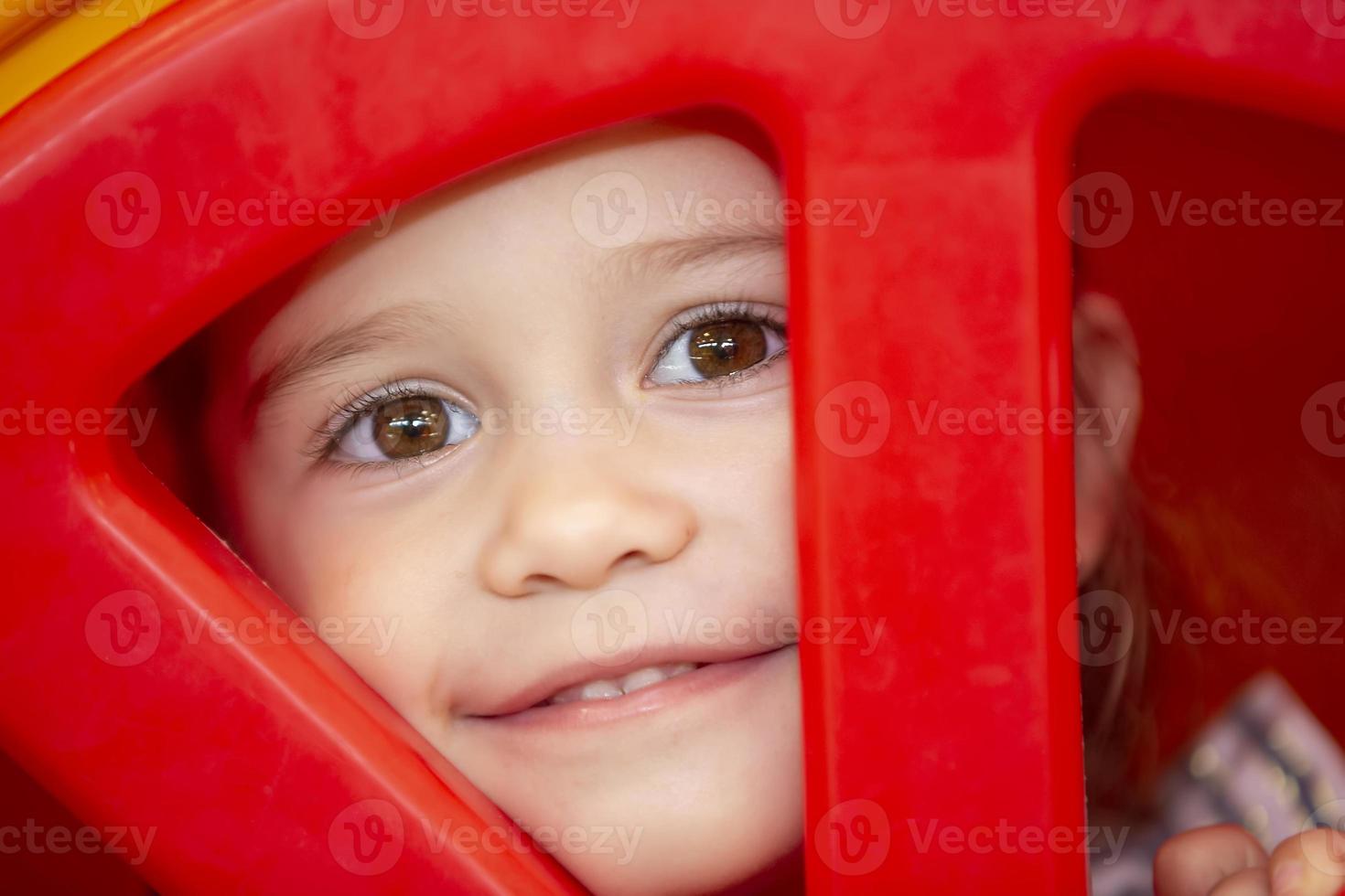 une peu fille coups d'oeil par une trou. le visage de une enfant dans une cercle. photo