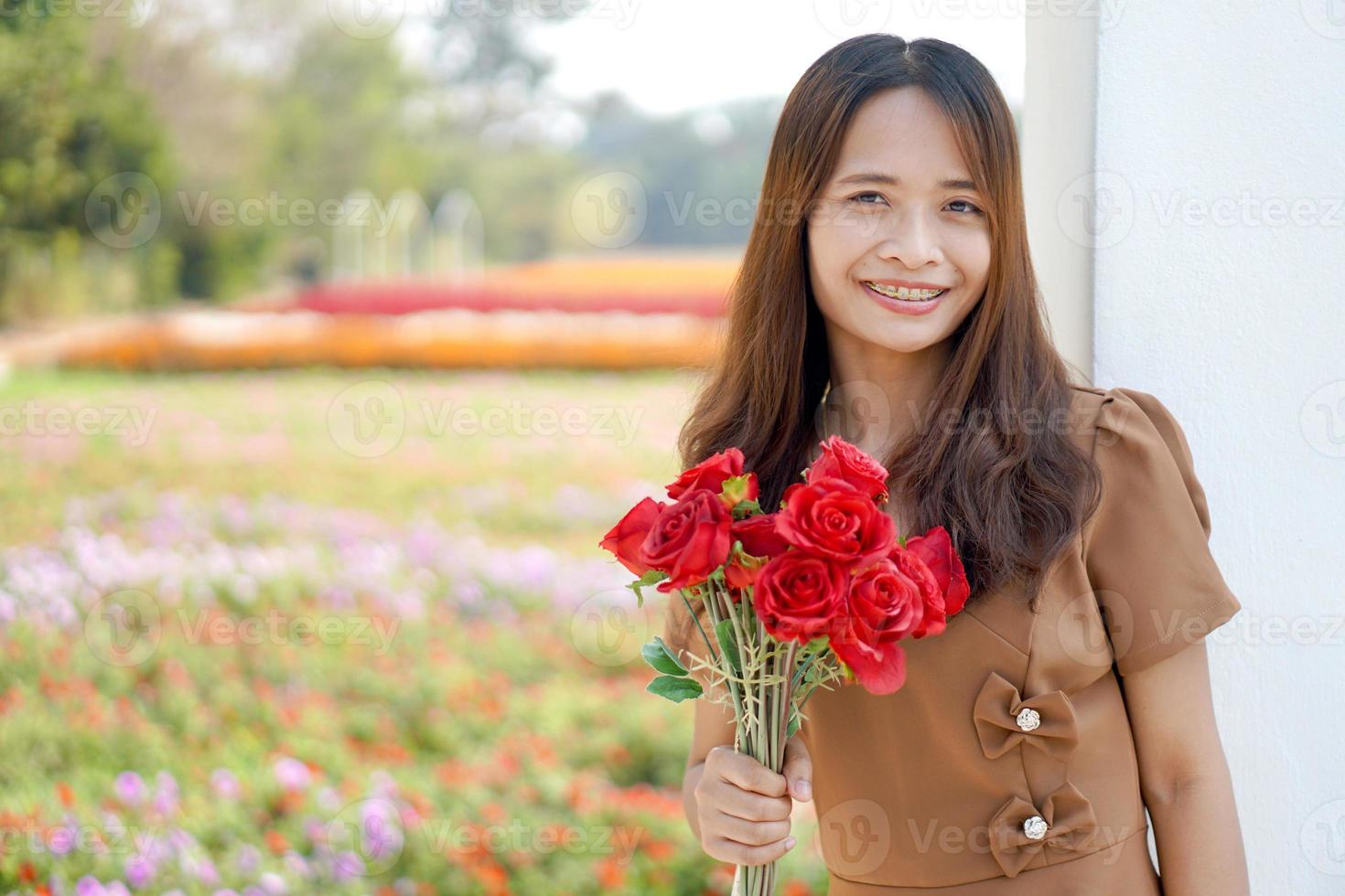 asiatique femme souriant Heureusement parmi magnifique fleurs photo