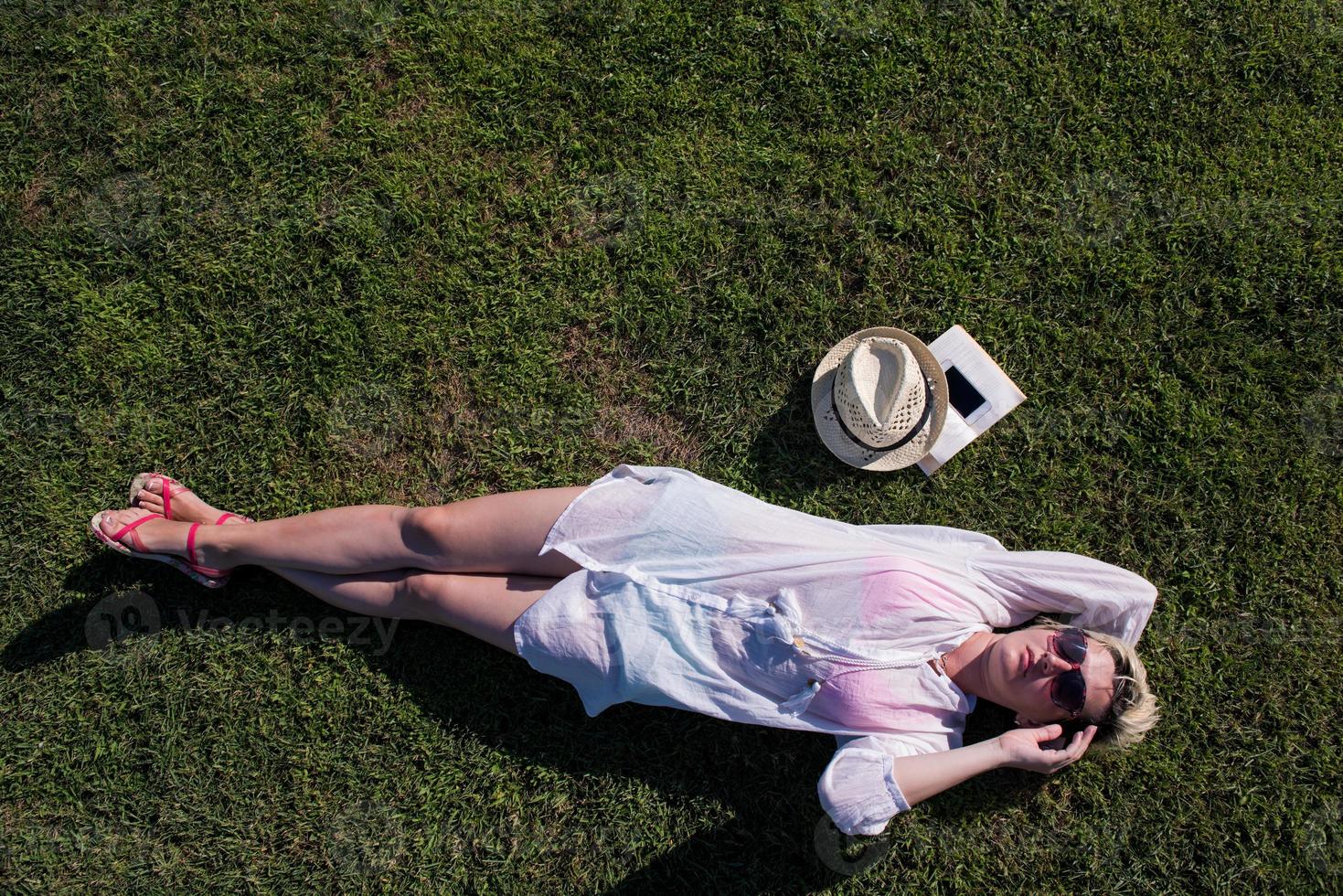 Haut vue de au dessus de une femme mensonge et relaxant sur une Prairie couvert avec vert herbe sur une ensoleillé été ou printemps journée. photo