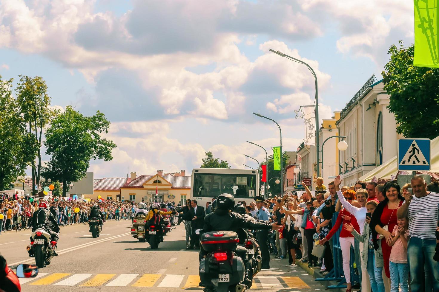 foule de gens salue une groupe de motocyclistes sur rue dans ville. moto parade sur été ensoleillé journée. photo