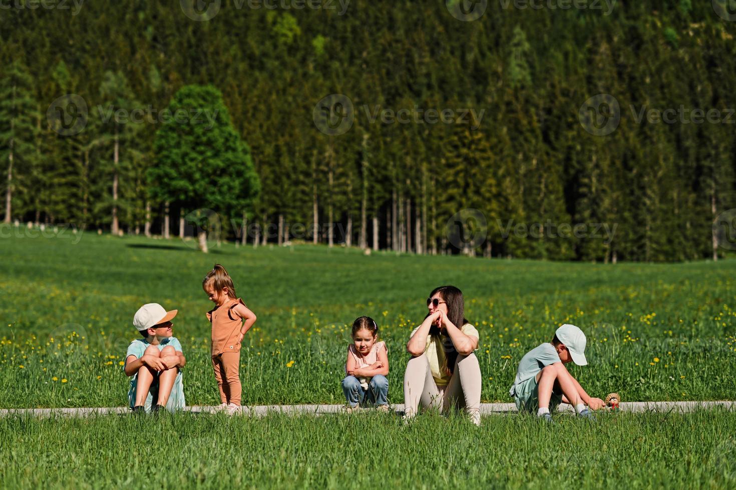 mère assise avec des enfants sur le chemin dans la prairie alpine à untertauern, autriche. photo