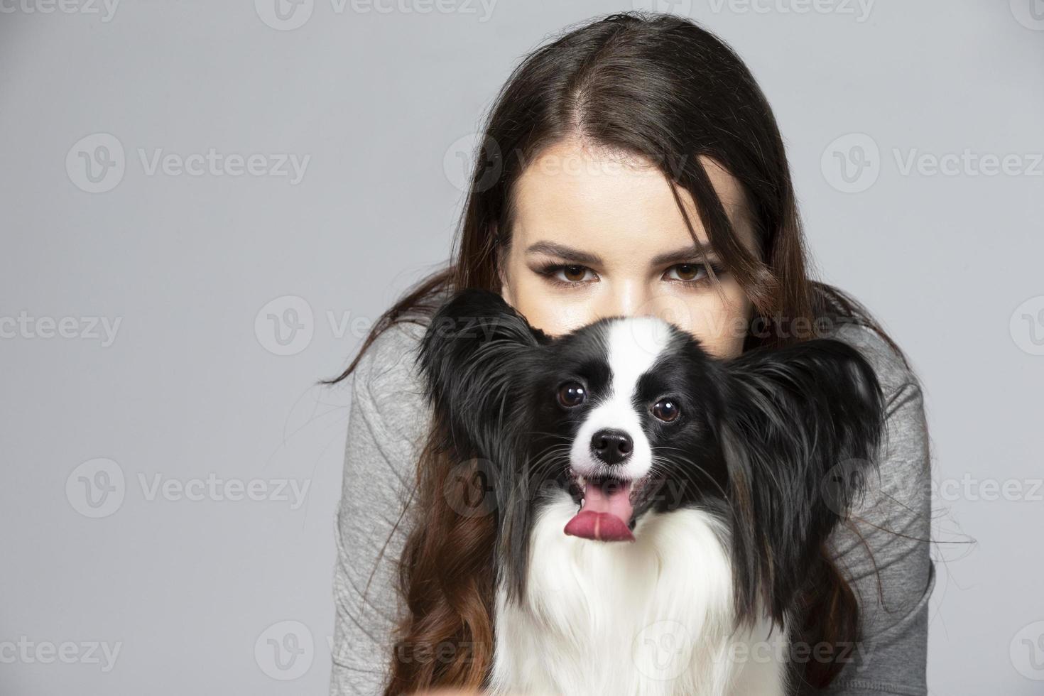 une mignonne Jeune femme est étreindre sa papillon chiot. le yeux de une magnifique fille et le yeux de une marrant chien avec gros oreilles. photo