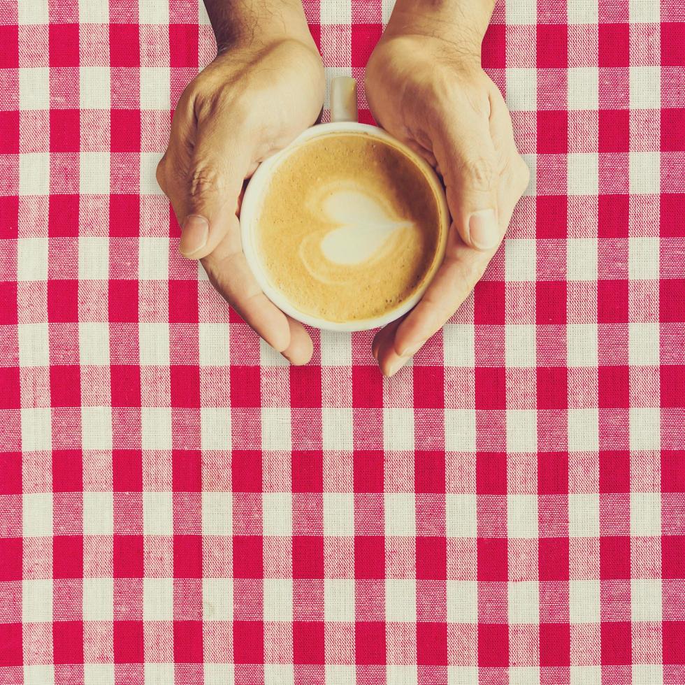 homme main en portant tasse café sur rouge et blanc tissu. photo