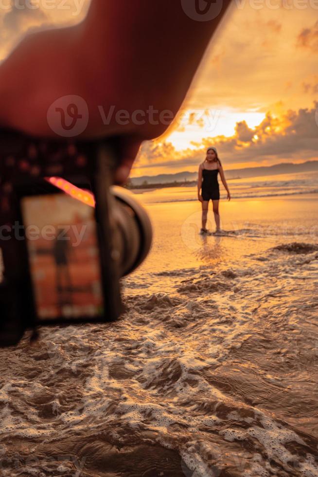 une caméra photographies un asiatique femme Faire une ballet Danse solitaire sur le plage photo