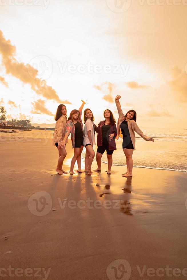 une groupe de asiatique femmes dans chemises posant Heureusement tandis que visite une magnifique plage photo