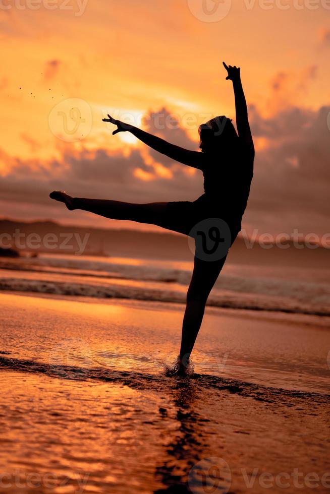 un indonésien femme dans silhouette Faire une magnifique Danse sur le plage avec le s'écraser vagues dans le après midi photo