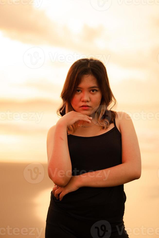 un asiatique femme avec blond cheveux et une noir robe pendaison en dehors solitaire sur le plage tandis que visite bali photo