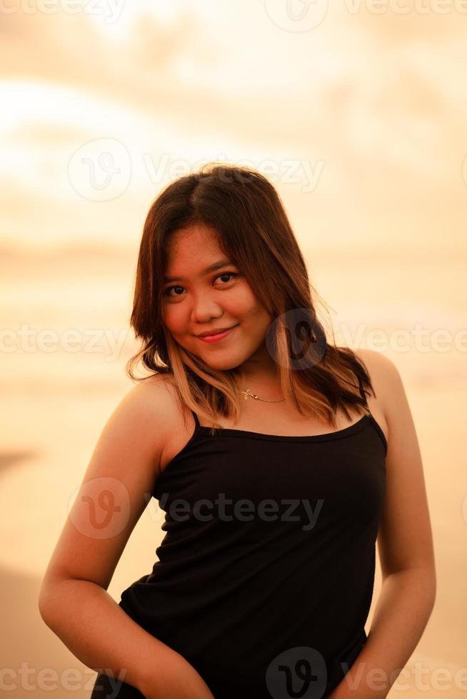 portrait de un indonésien femme dans noir vêtements et blond cheveux posant très magnifiquement sur le plage photo