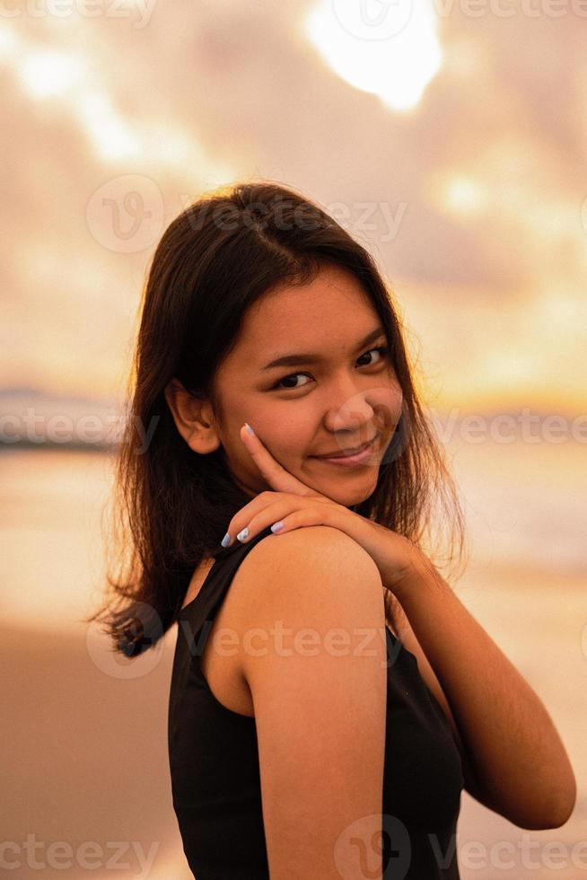 un asiatique adolescent femme avec une noir chemise et noir cheveux a une mignonne visage lorsque elle sourit et jouit le vue photo