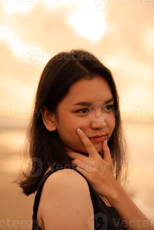 un asiatique adolescent femme avec une noir chemise et noir cheveux a une mignonne visage lorsque elle sourit et jouit le vue photo