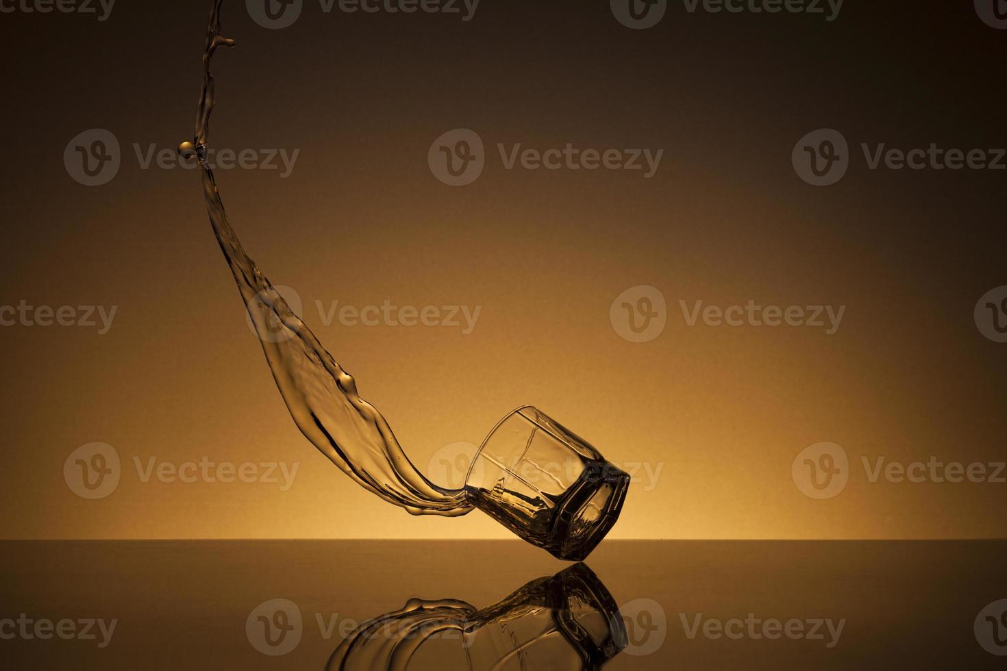 chute verre de alcoolique boisson sur une d'or Contexte photo