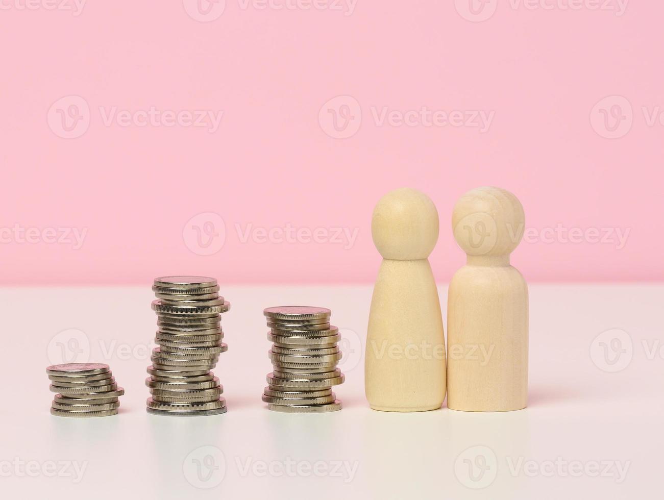 une empiler de métal pièces de monnaie et en bois Les figures de Hommes sur une blanc tableau. des économies et dépenses, famille budget, subventions de le Etat photo