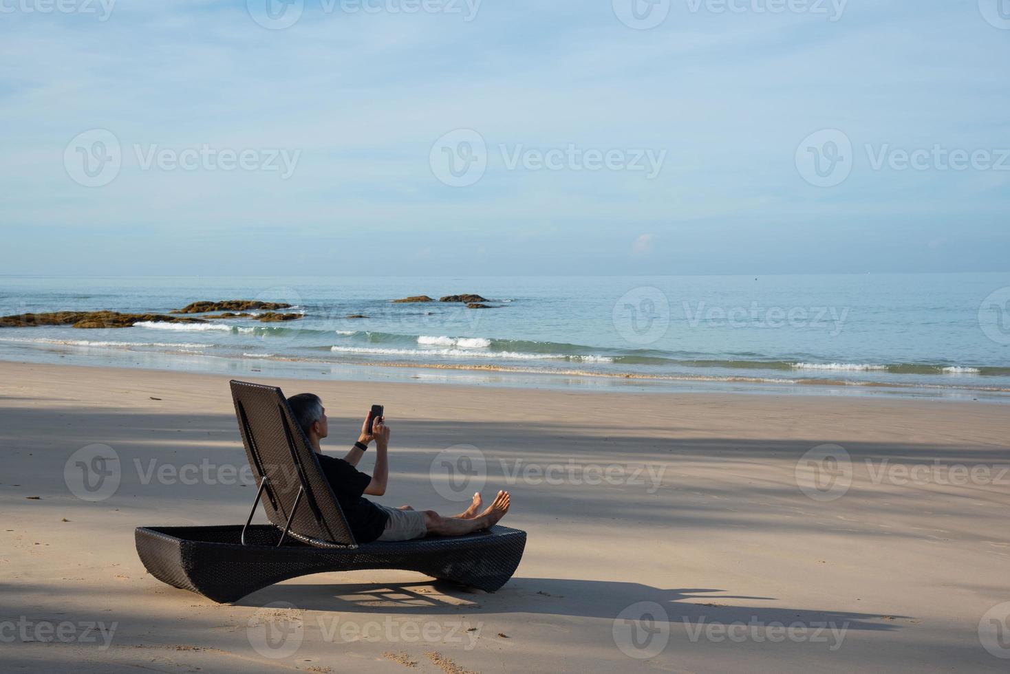 une Sénior adulte en utilisant téléphone portable sur le plage photo