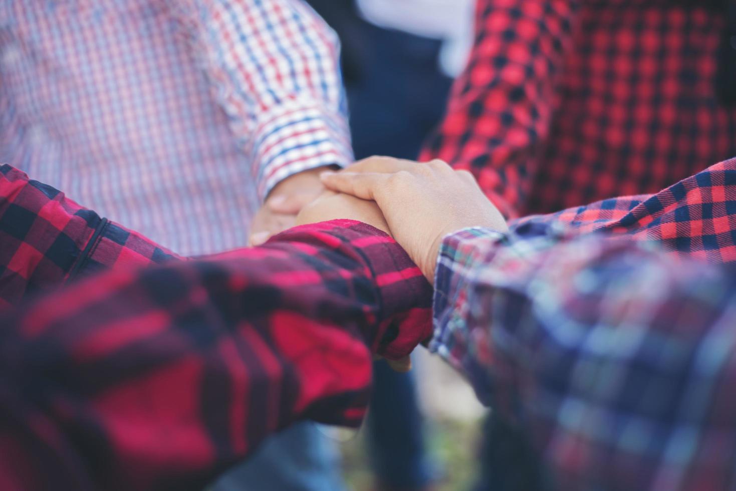 vue rapprochée de jeunes gens mettant leurs mains ensemble photo