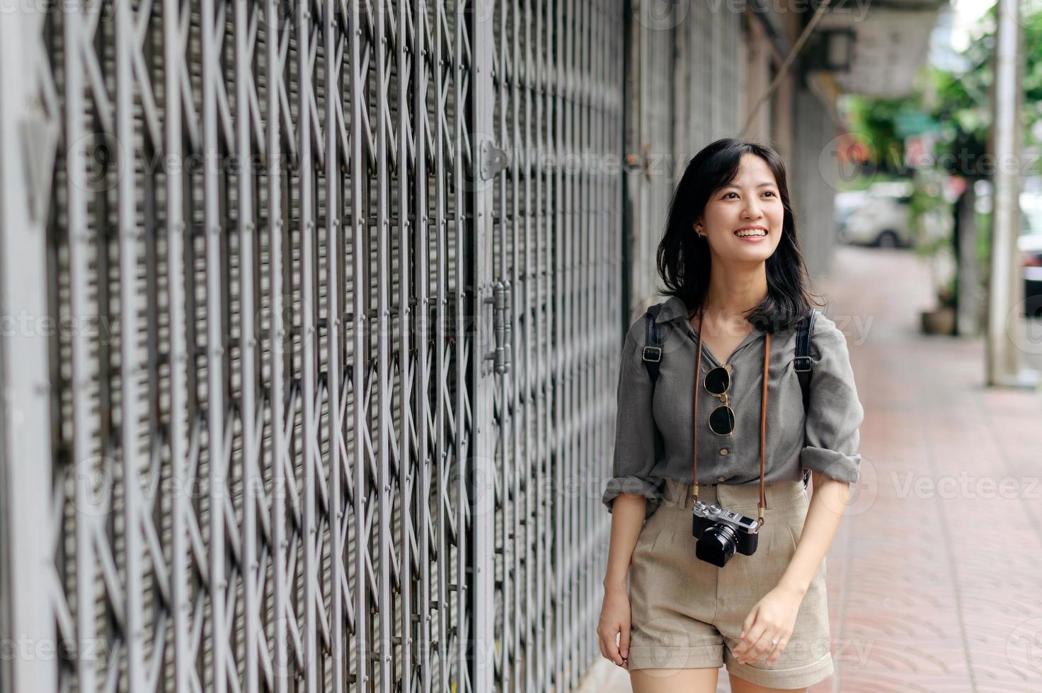 Jeune asiatique femme sac à dos voyageur profiter rue culturel local endroit et sourire. voyageur vérification en dehors côté des rues. photo