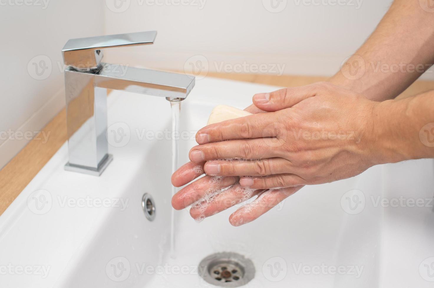 Pour des hommes mains avec savon en dessous de une courant de l'eau dans le lavabo photo