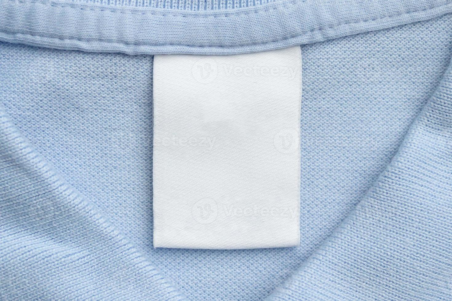 étiquette blanche de vêtements de soin de blanchisserie vierge sur fond de tissu de chemise bleue photo