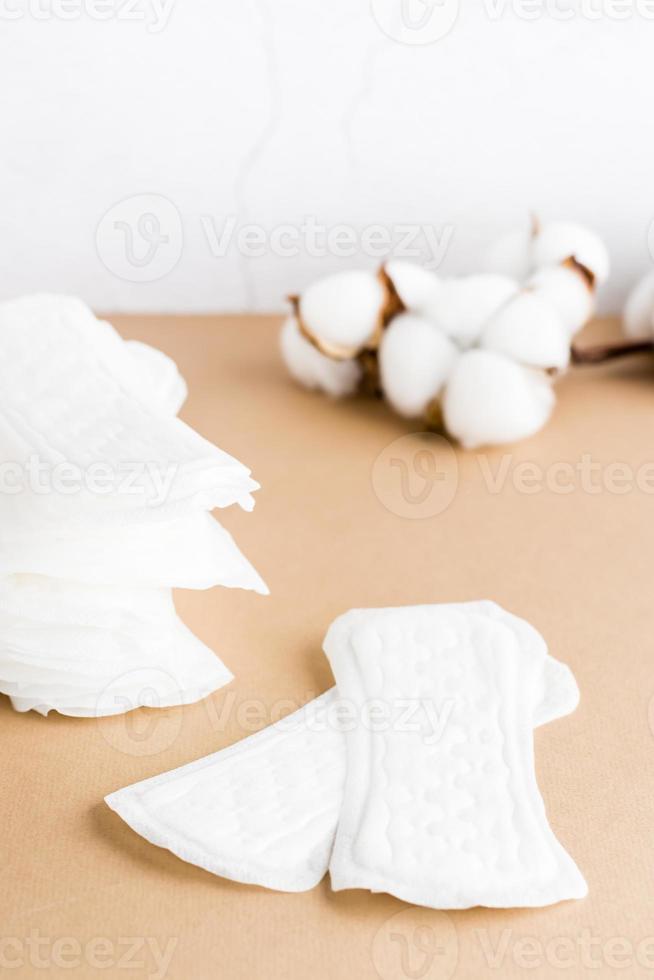 nettoyer jetable sanitaire tampons et une branche de coton sur une beige Contexte. aux femmes santé et confort concept photo