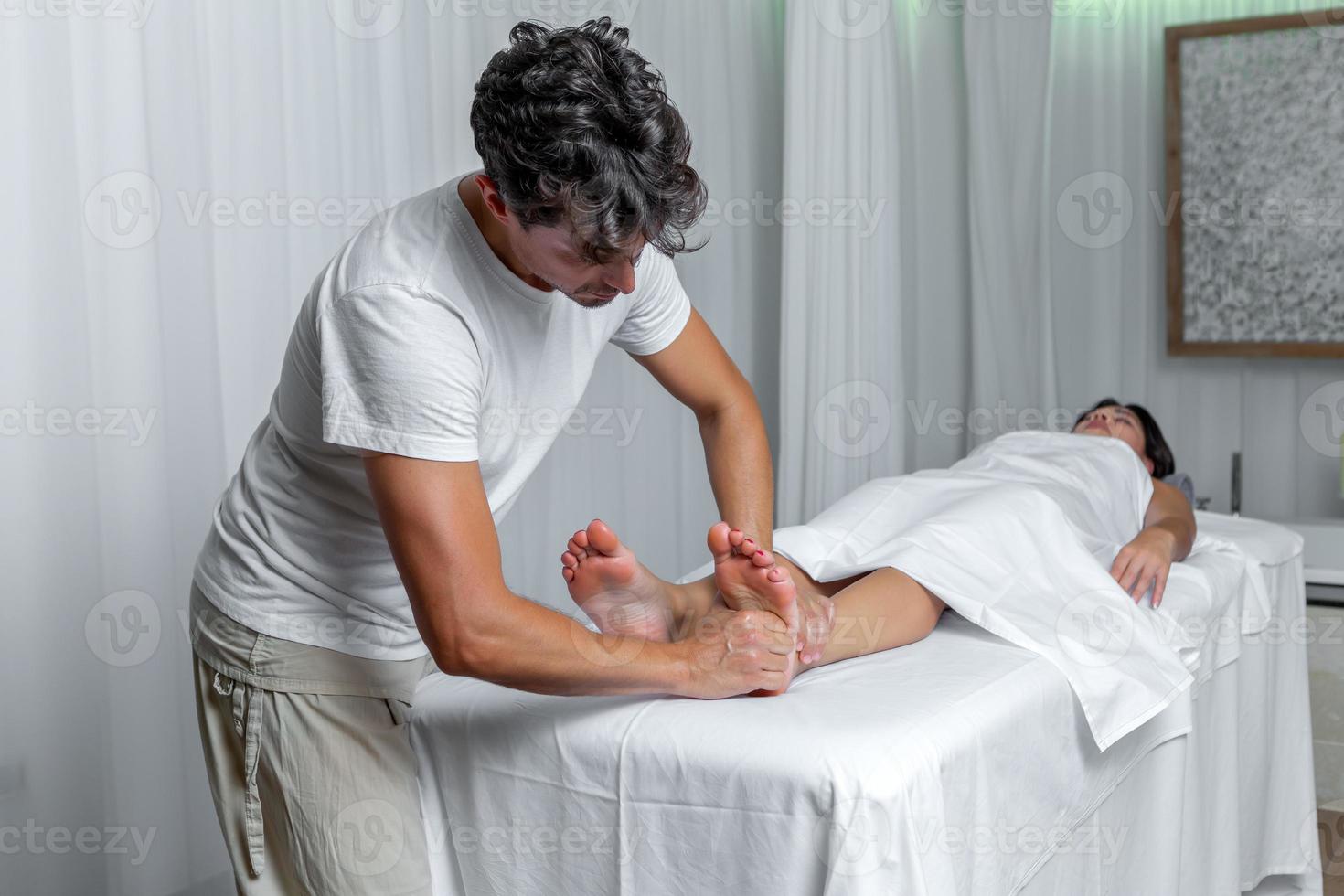 Masculin masseur appliquant pression à pied de femme dans réflexologie massage à spa photo