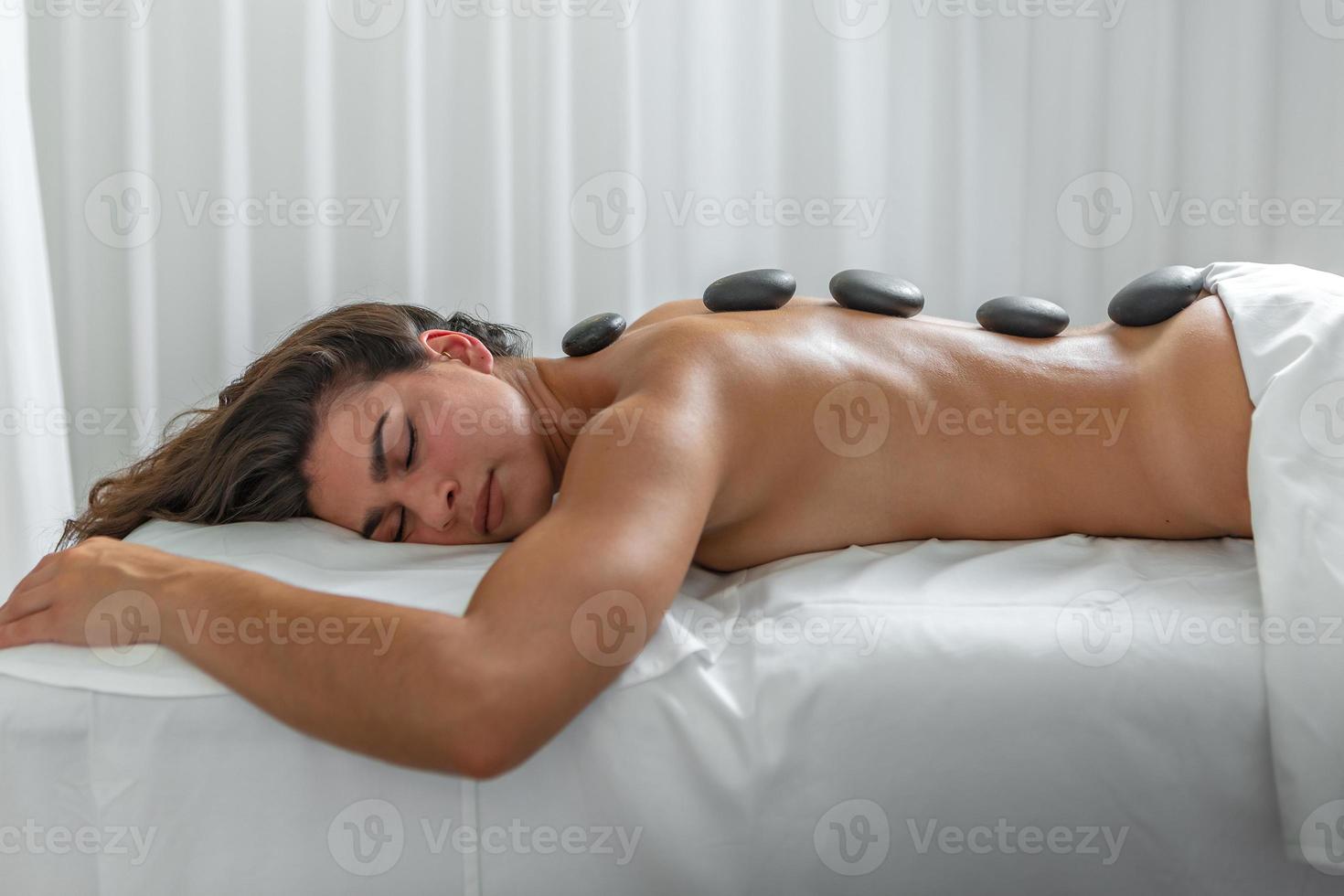 calme femme avec chaud des pierres dans sa retour pour massage retour traitement dans spa salon photo
