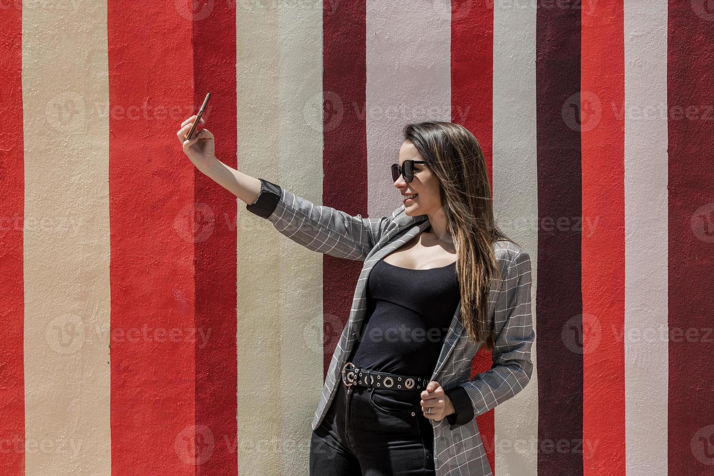 élégant femme prise selfie dans ville sur ensoleillé journée photo
