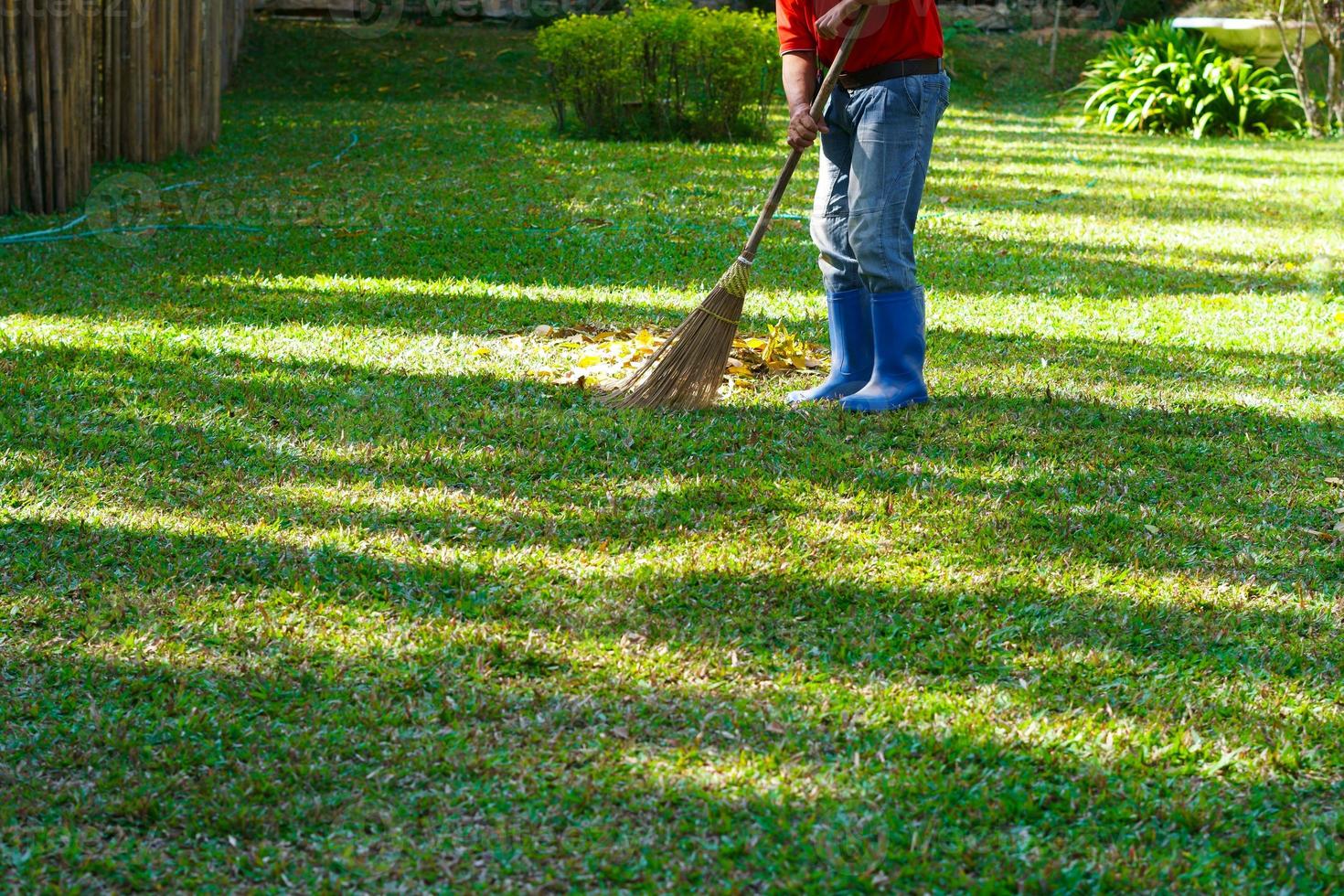 une homme ouvrier balaie feuilles dans le Publique parc photo