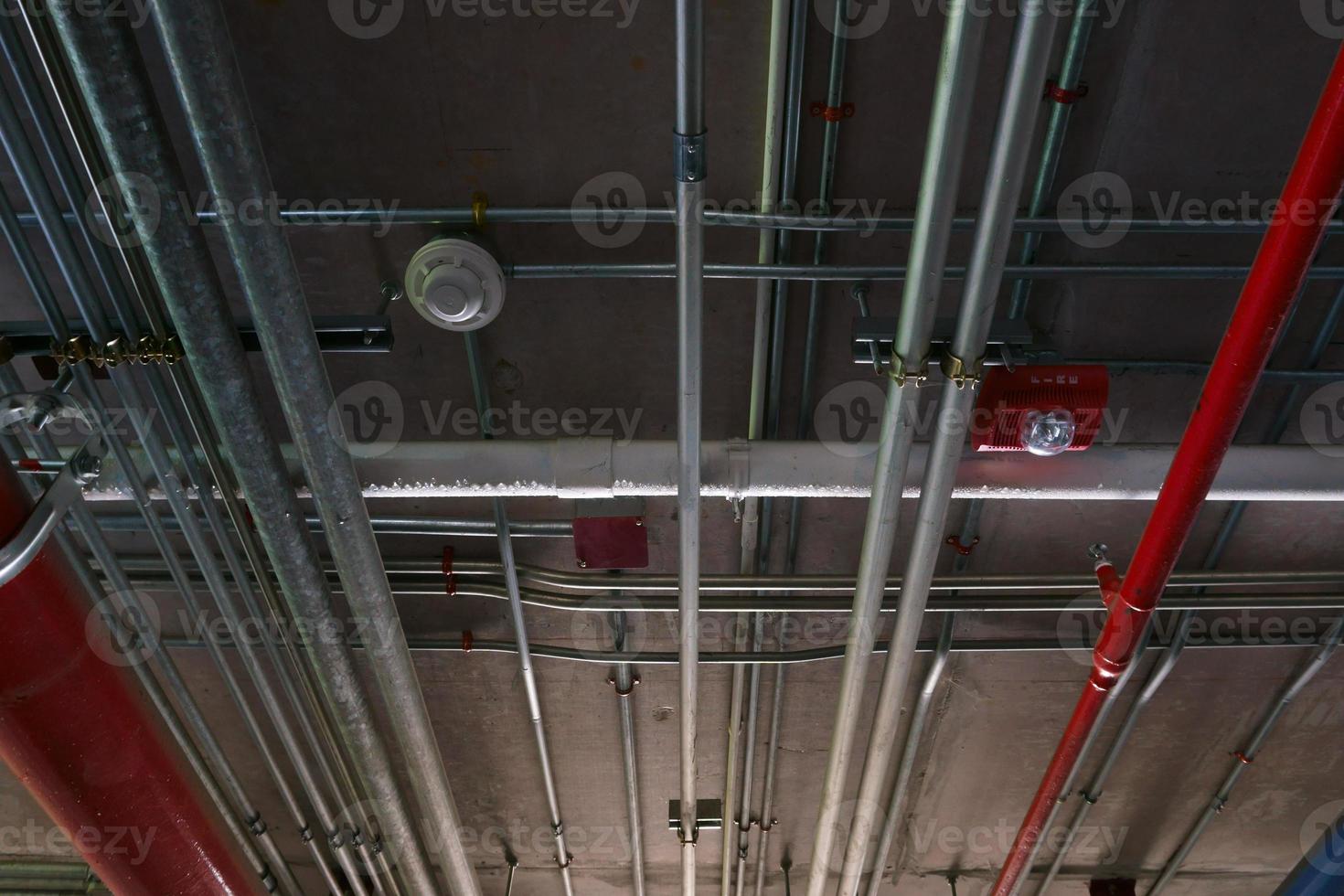 tuyaux de système sanitaire et câbles électriques installés sous une structure en béton armé de dalles plates dans le bâtiment.tuyaux de ventilation dans un parking souterrain photo