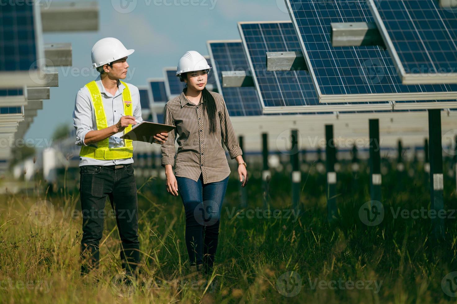 jeune inspecteur asiatique ingénieur homme et femme marchant vérifiant l'opération dans une ferme solaire photo