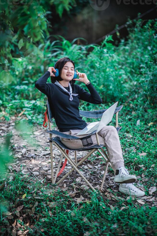 jeune femme portant un casque écoutant de la musique depuis un ordinateur portable photo