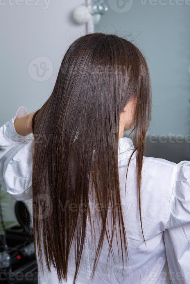 une chevelure brune droite et saine qui a subi la procédure de lissage des cheveux. cheveux bruns lisses, brillants et sains photo