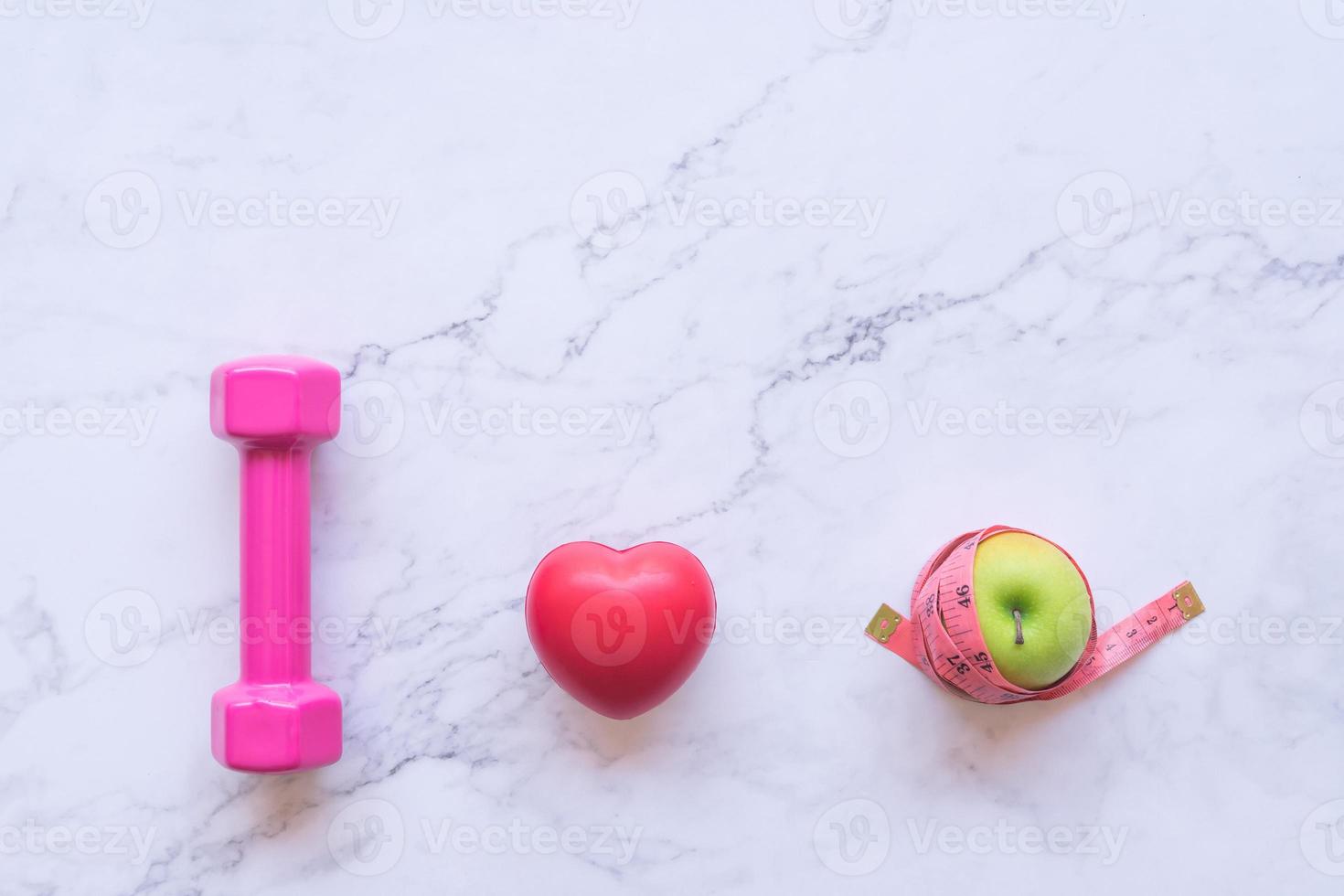haltère rose, coeur rouge et pomme sur fond de marbre photo