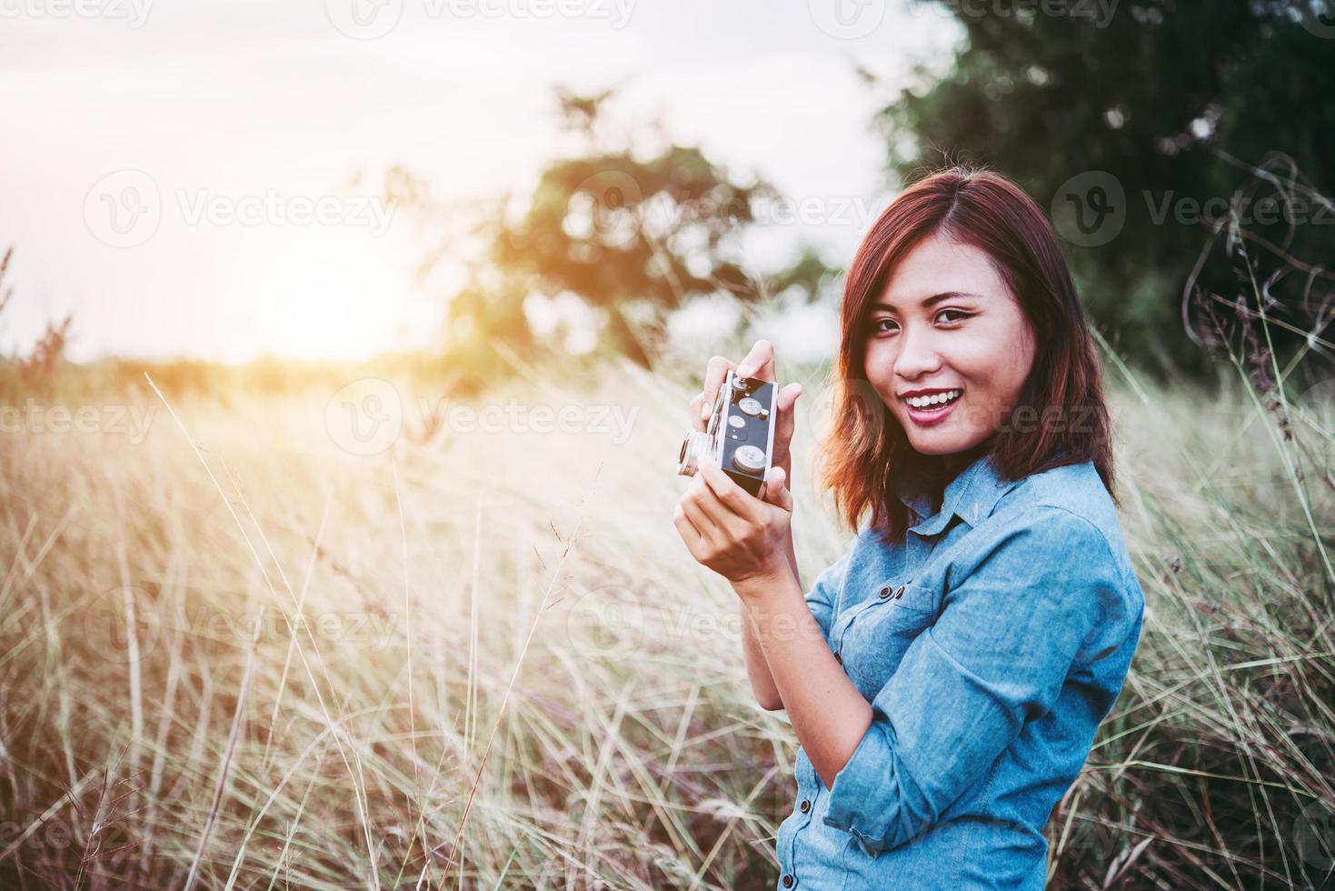 femme heureuse jeune hipster avec appareil photo vintage dans le champ