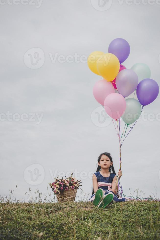 petite fille jouant avec des ballons sur champ de prairie photo