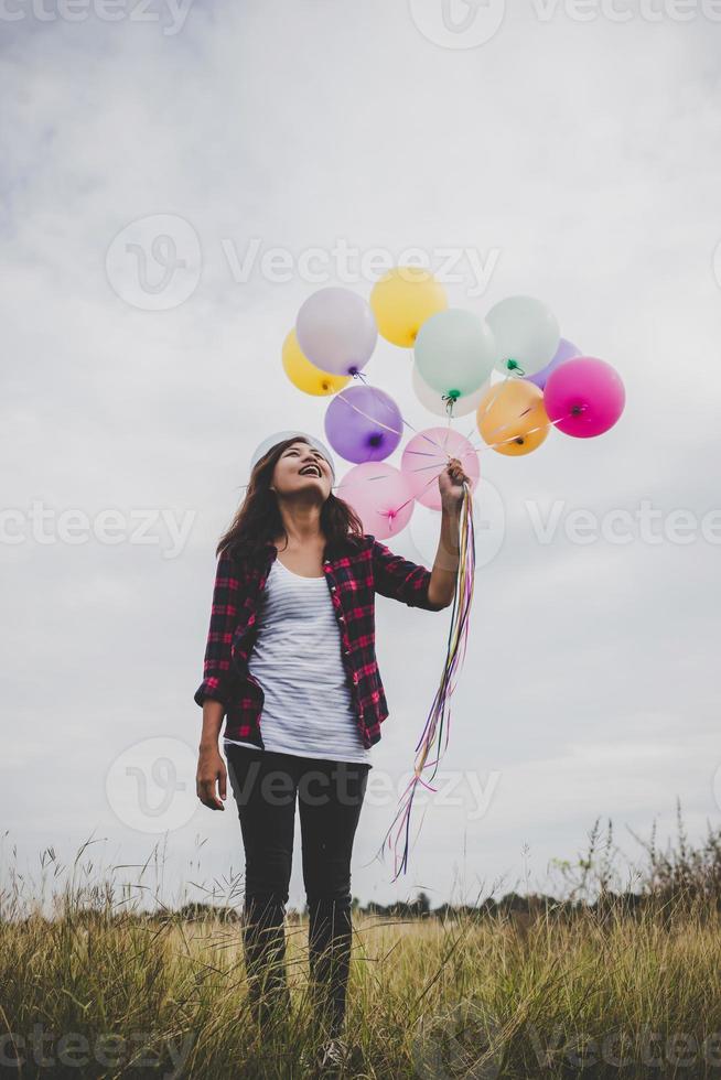 belle jeune femme hipster tenant des ballons colorés à l'extérieur photo