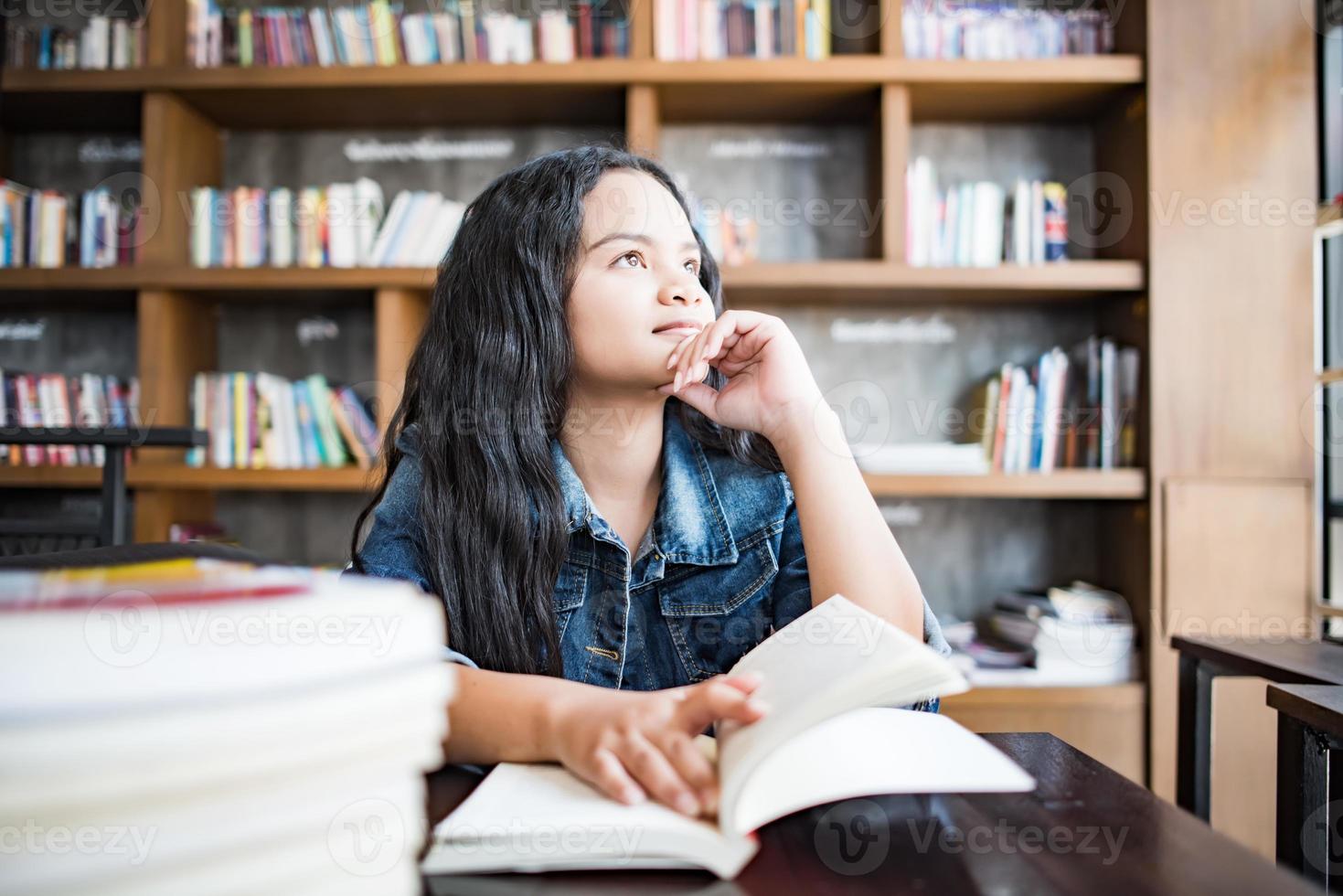 Jeune femme lisant un livre assis à l'intérieur dans un café urbain photo