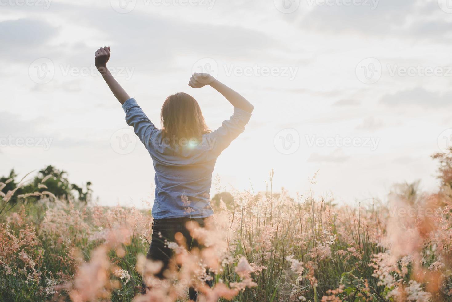 Belle jeune femme étend ses bras en l'air dans un champ photo