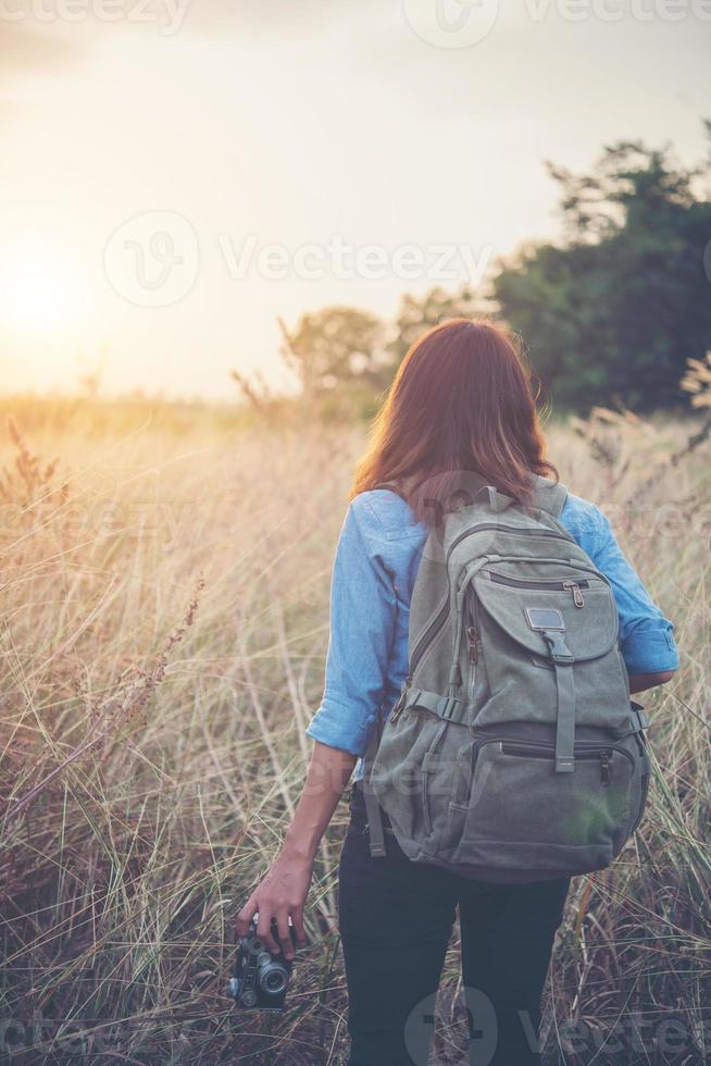 Routard femme jeune hipster avec un appareil photo vintage debout dans un champ