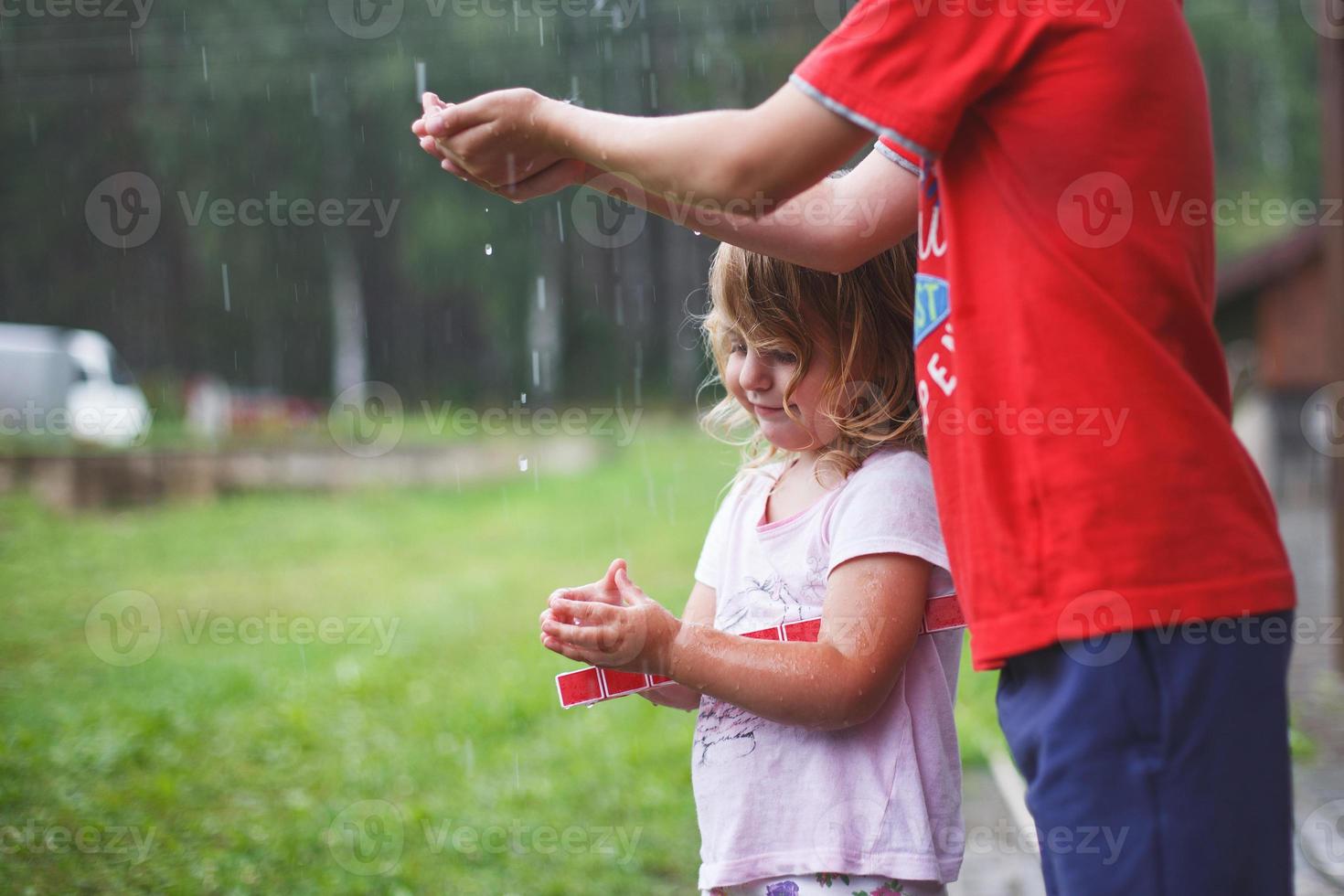 frère et sœur jouer dans pluvieux temps les enfants sauter dans flaque et boue dans le pluie. photo