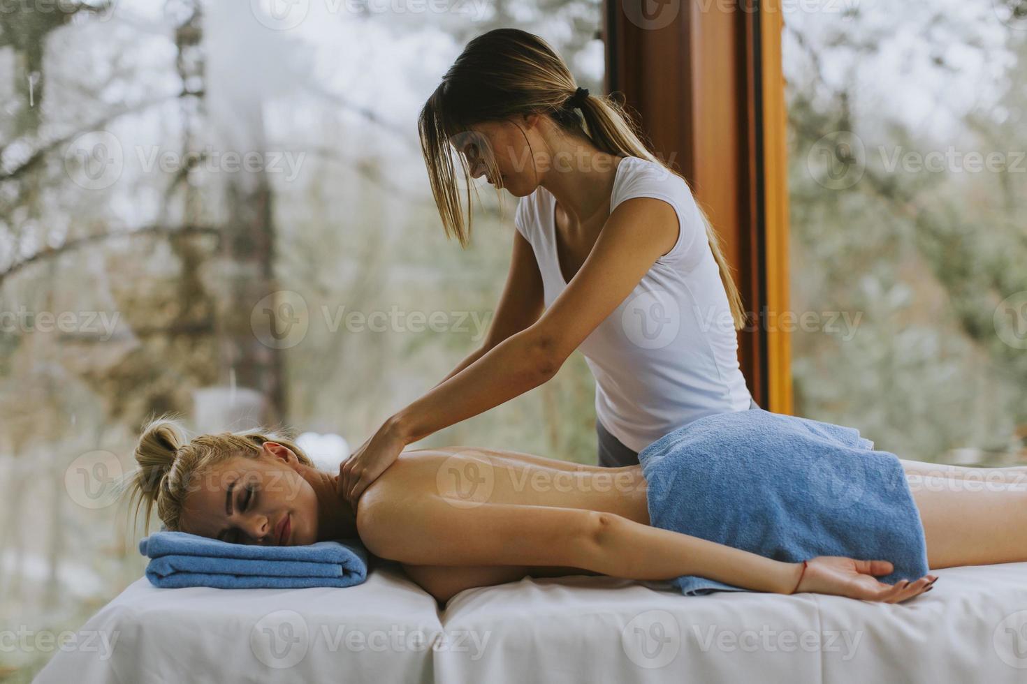 Belle jeune femme allongée et ayant un massage du cou dans un salon spa pendant la saison d'hiver photo