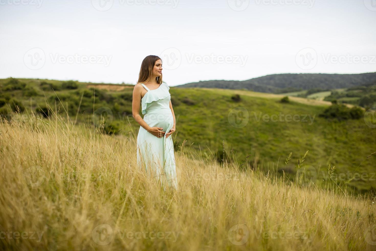 jeune femme enceinte se détendre à l'extérieur dans la nature photo