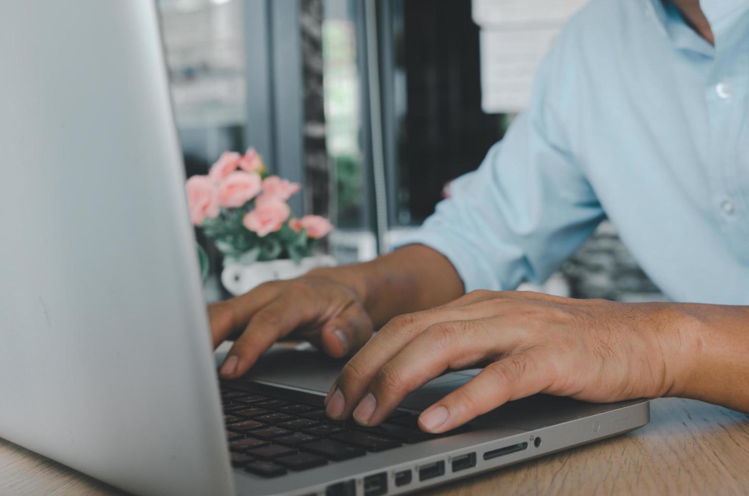 Un homme d'affaires en tapant sur un clavier d'ordinateur portable sur la table à la recherche sur Internet photo