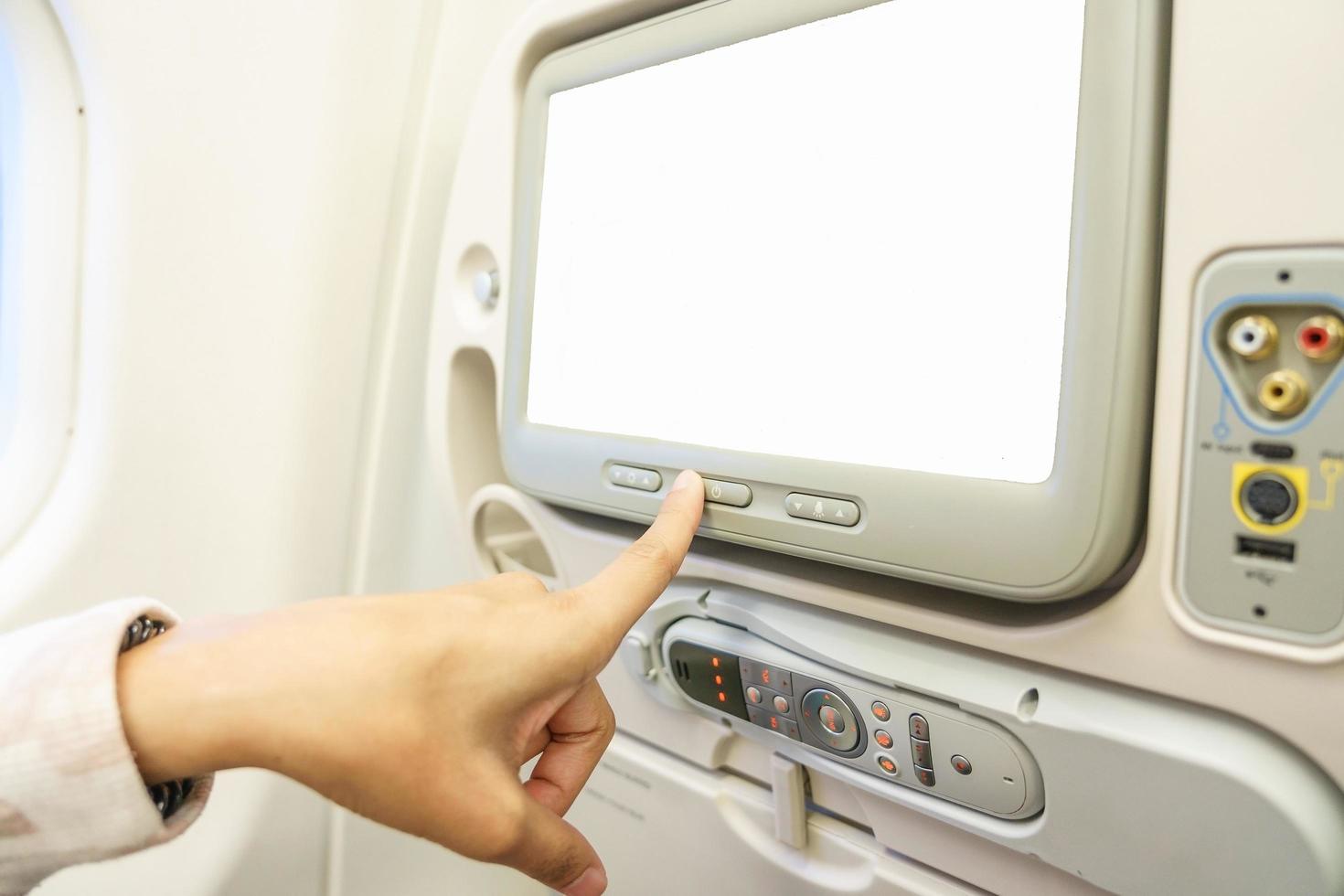 Femme pointant le doigt sur un écran lcd blanc blanc sur un avion photo