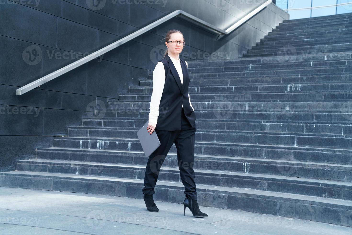 femme agent immobilier dans veste des promenades vers le bas escaliers avec portable et téléphone dans sa main photo