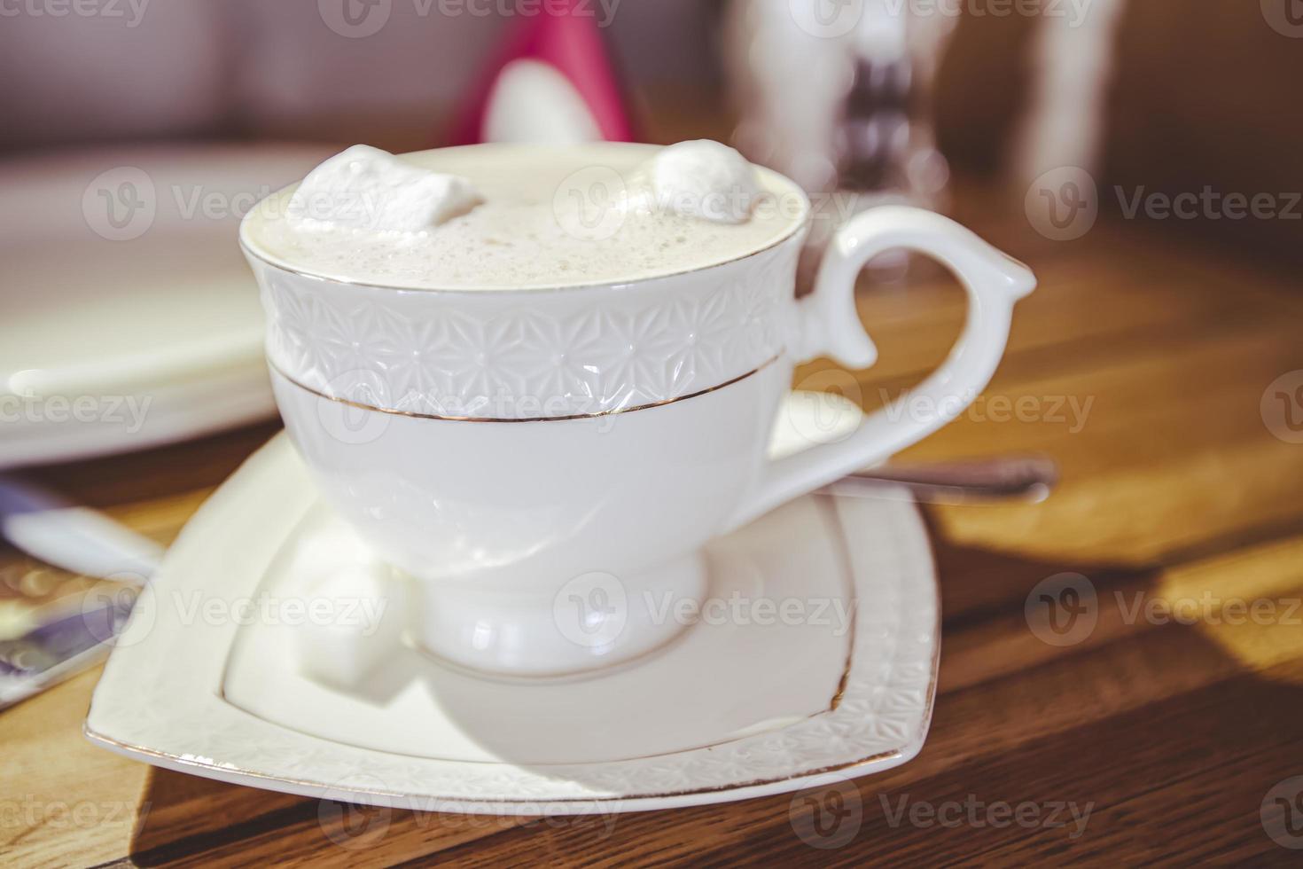 une tasse en porcelaine blanche avec du cappuccino se dresse sur une table dans un bar. photo