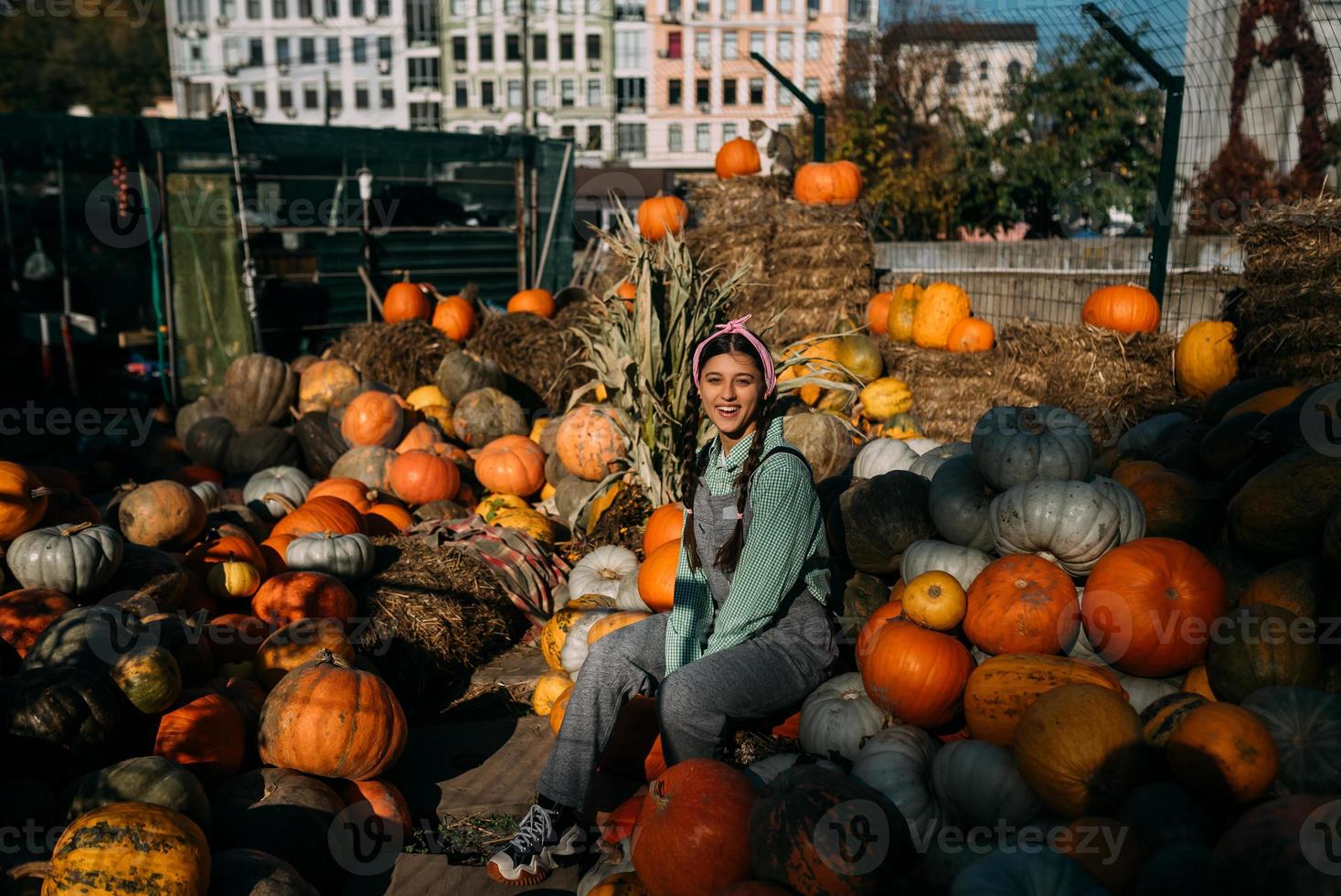 jeune agricultrice est assise parmi un grand nombre de citrouilles photo