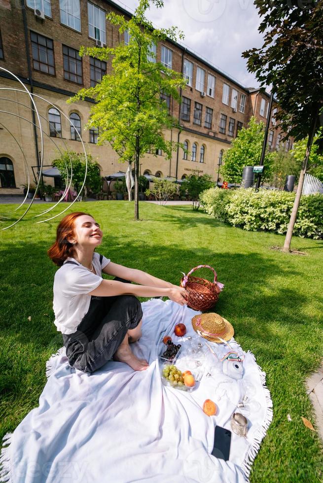 heureuse jeune femme assise sur une couverture sur la pelouse du parc photo