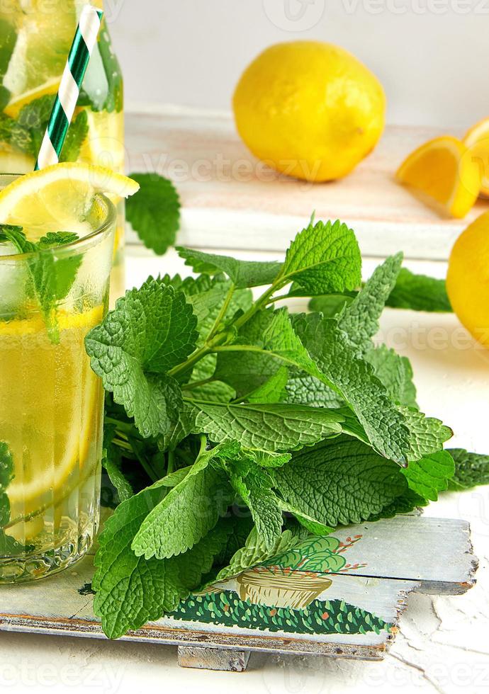 Frais bouquet de menthe et une verre avec limonade sur une en bois planche photo