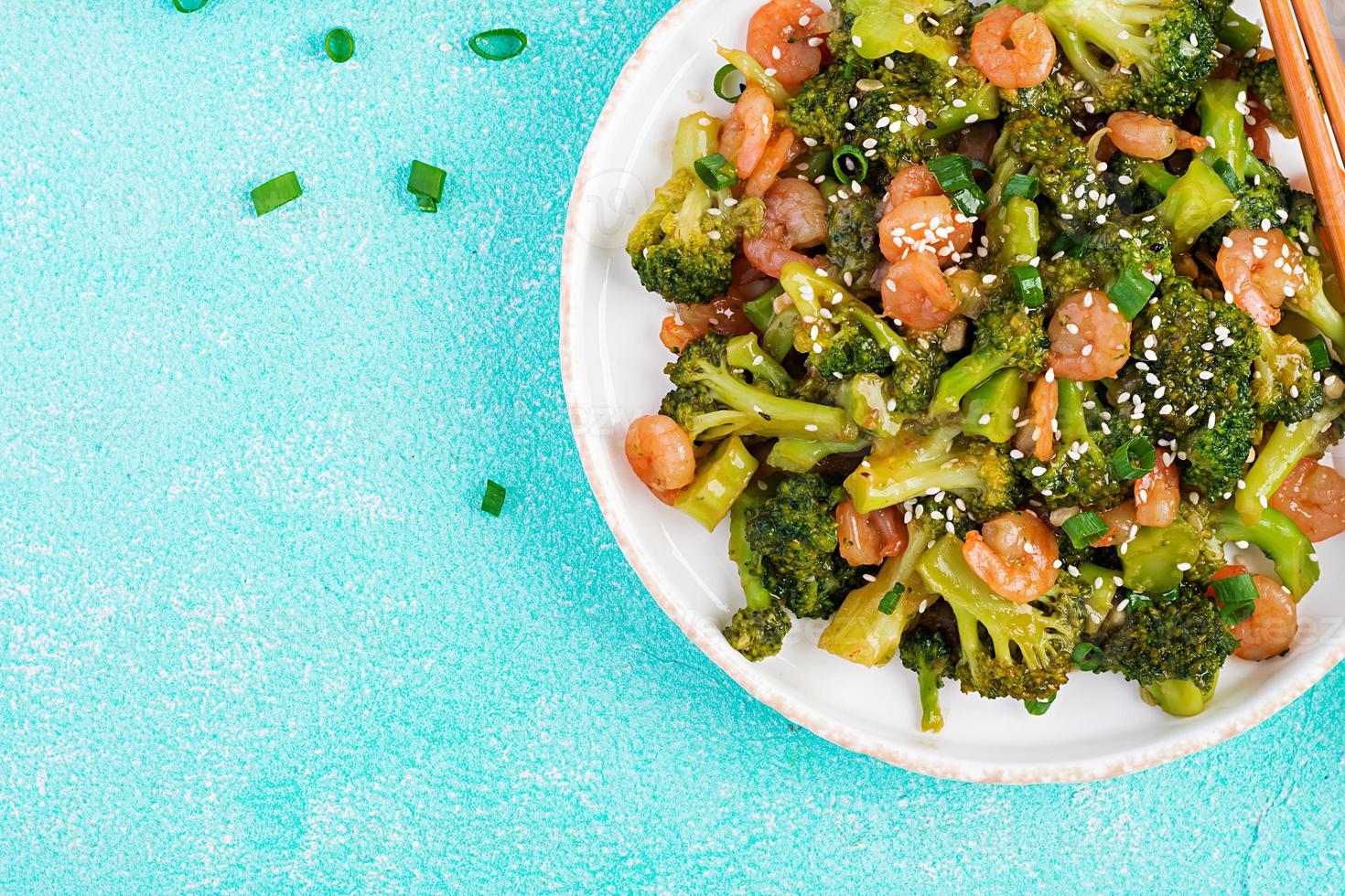 remuer frire crevette avec brocoli proche en haut sur une plaque. crevettes et brocoli. Haut voir, aérien photo