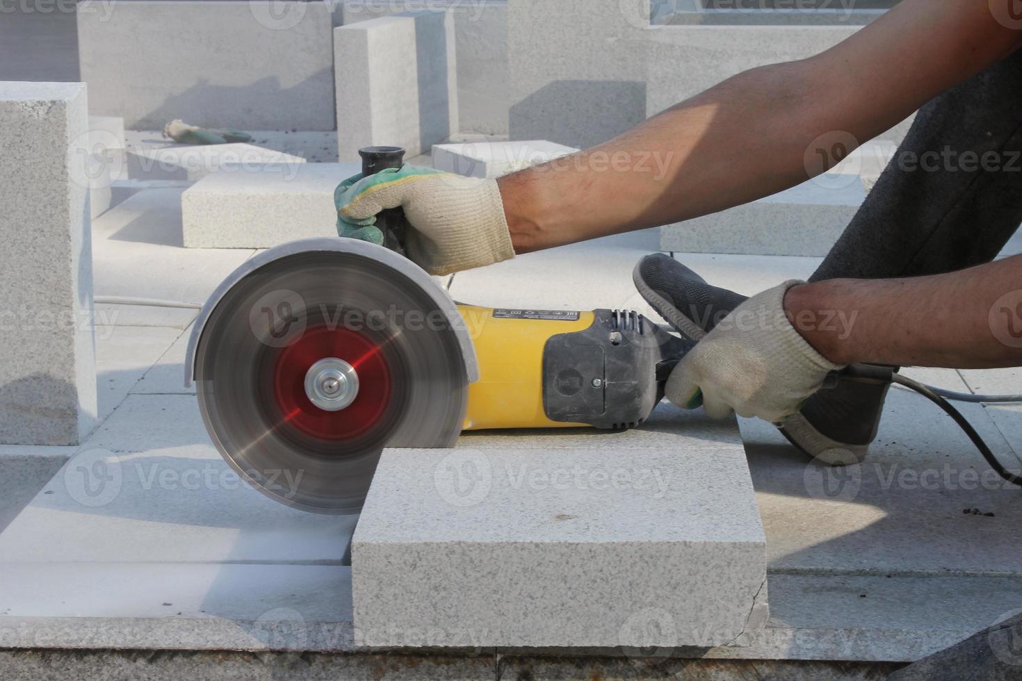 mains de travailleur avec des garnitures de broyeur électrique dalles de pavage sur le chantier de construction. concept de pose de nouvelles dalles de trottoir. équipement de taille de pierre. travaux routiers. travaux publics. réparer l'asphalte. fermer photo